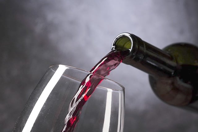 bottle pouring red wine into glass