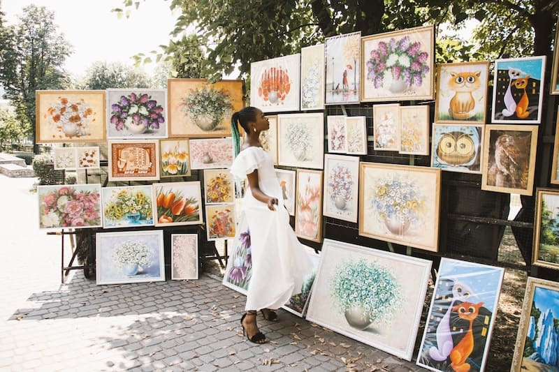 Tips for Buying Authentic Art and Avoiding Fakes, woman looking at art in an art fair